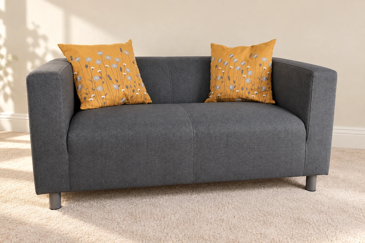 Compact grey sofa with mustard botanical upholstery panels.